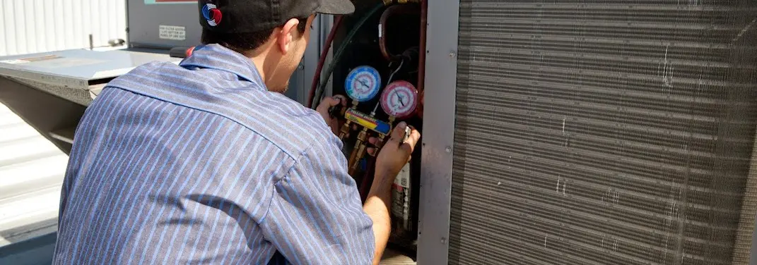 HVAC technician servicing a condenser unit in Ypsilanti